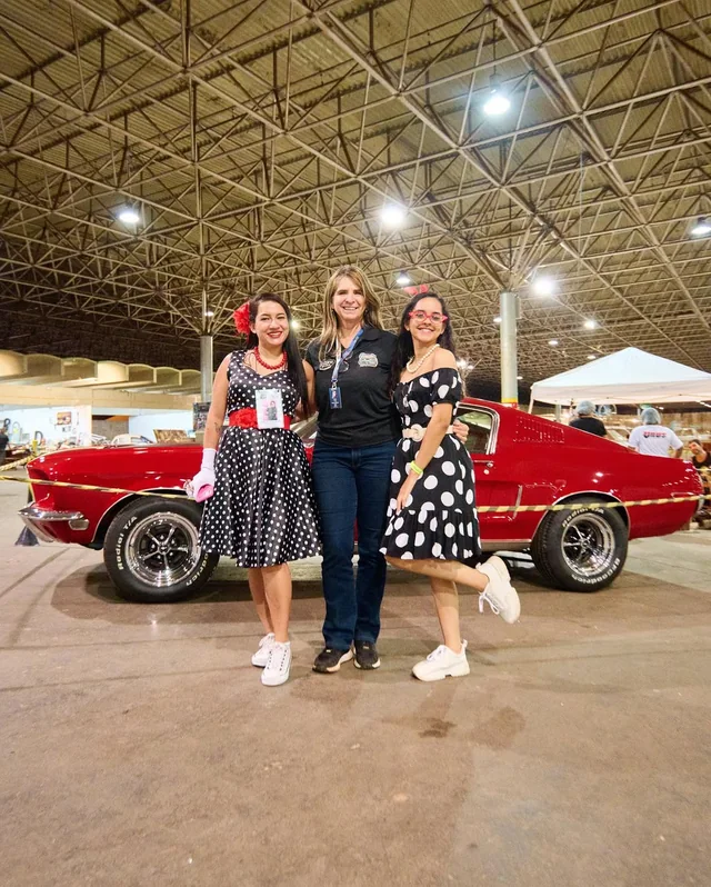 Visitantes junto a um carro vermelho