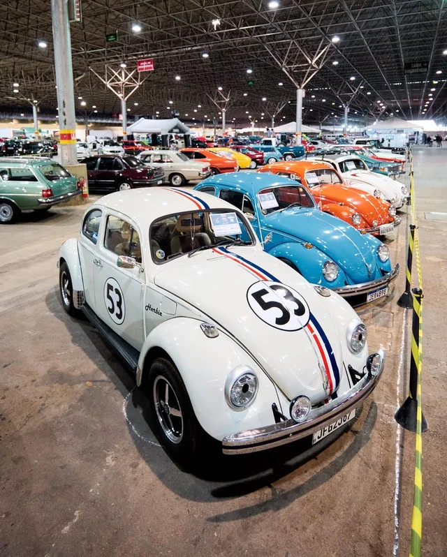 Fusca branco entre carros no pavilhão